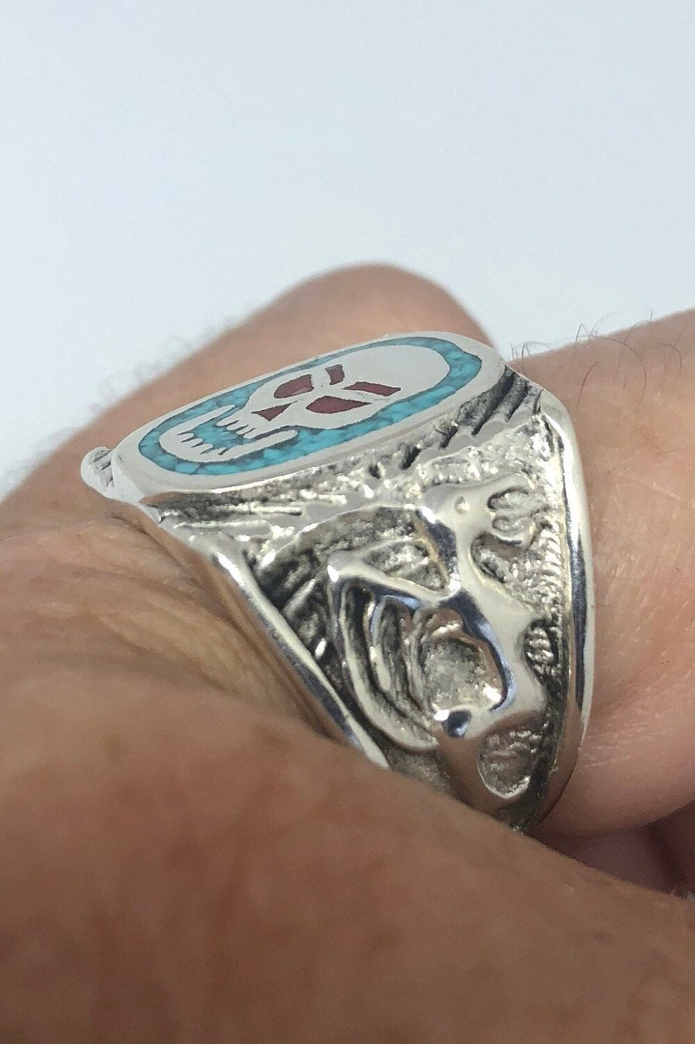 Skull ring with blue turquoise and red coral in white bronze on finger