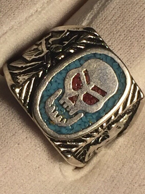 Skull ring with blue turquoise and red coral in white bronze on white gloves